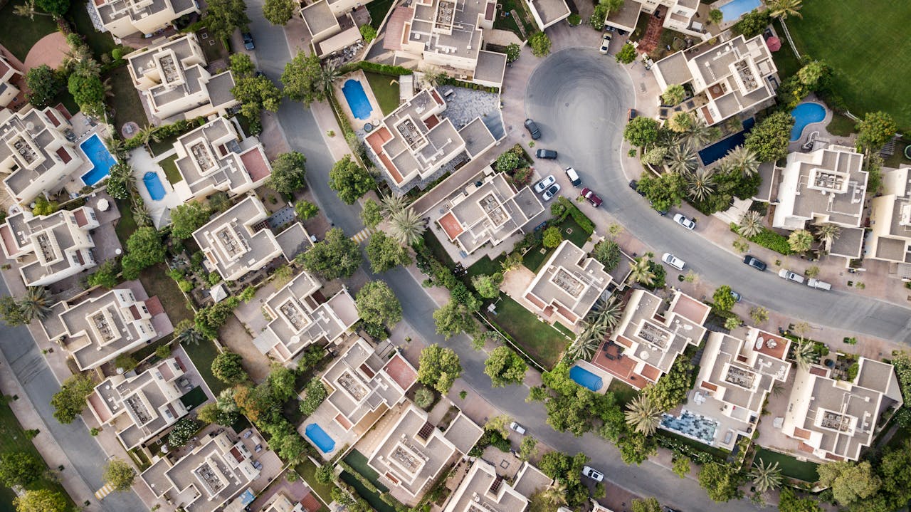our-story Explore a stunning aerial view of a residential area in Dubai with lush greenery and swimming pools.